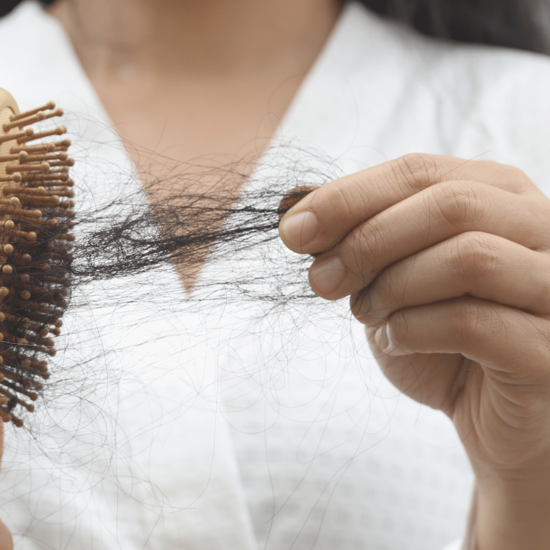 Hair thinning women picutre holding brush with a lot of hair in it