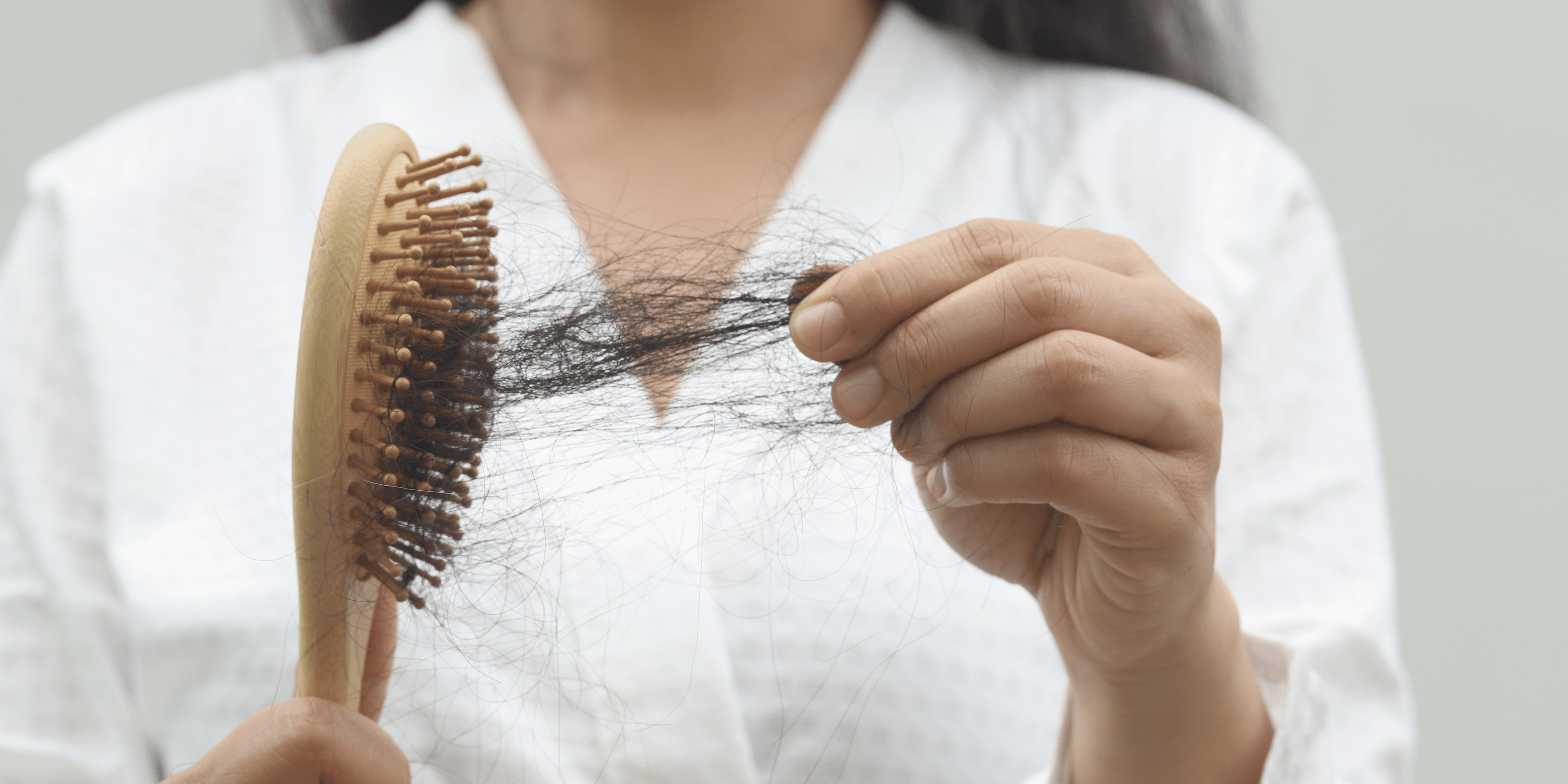 Hair thinning women picutre holding brush with a lot of hair in it